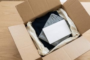 Открытая посылка с аккуратно сложенной одеждой на столе